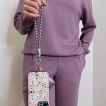 woman holding the Hobo lasso phone wristlet in metallic leather, color pewter spur against a white background. 