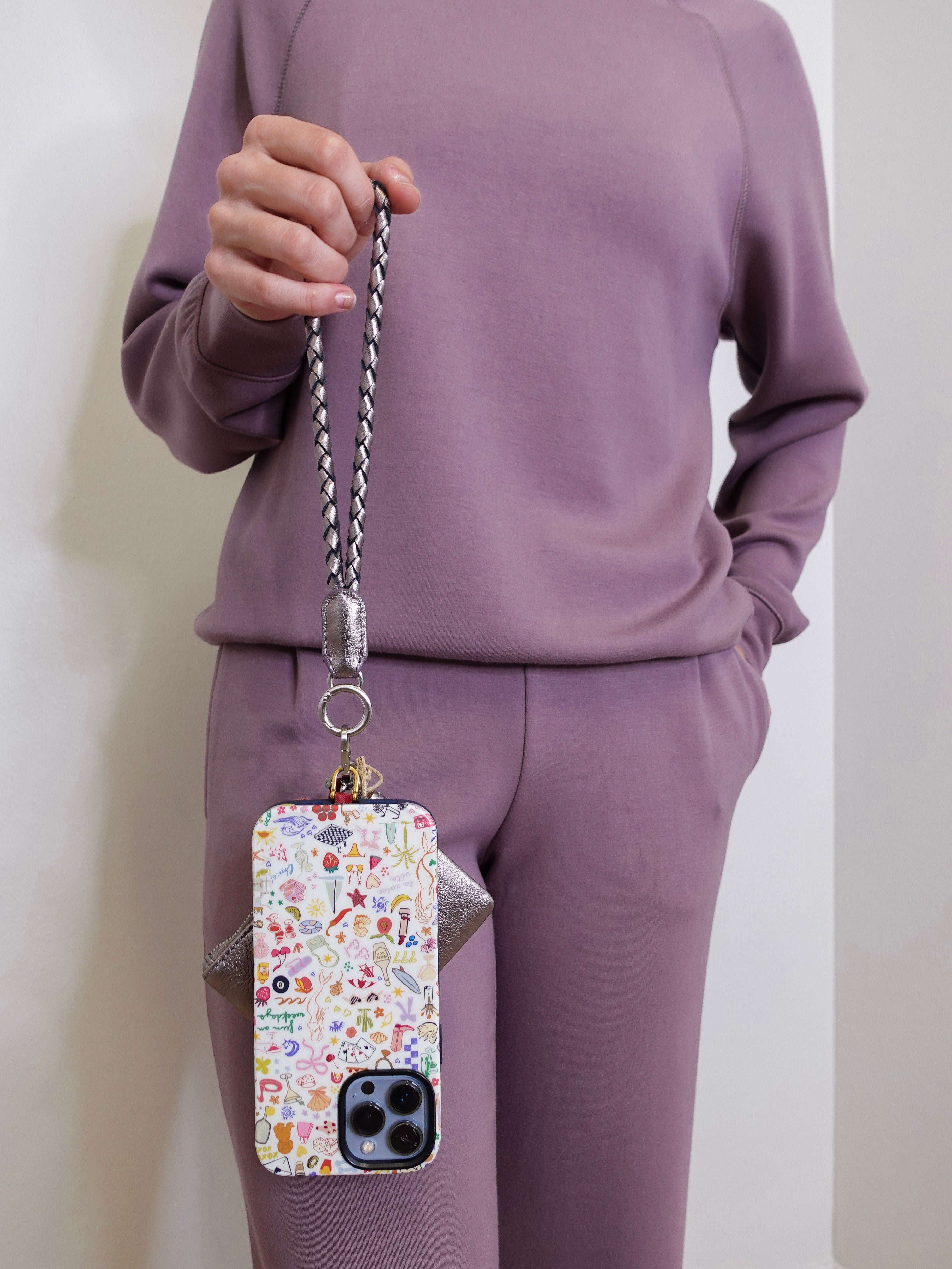 woman holding the Hobo lasso phone wristlet in metallic leather, color pewter spur against a white background. 