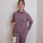 woman holding the Hobo lasso phone wristlet in metallic leather, color pewter spur against a white background. 