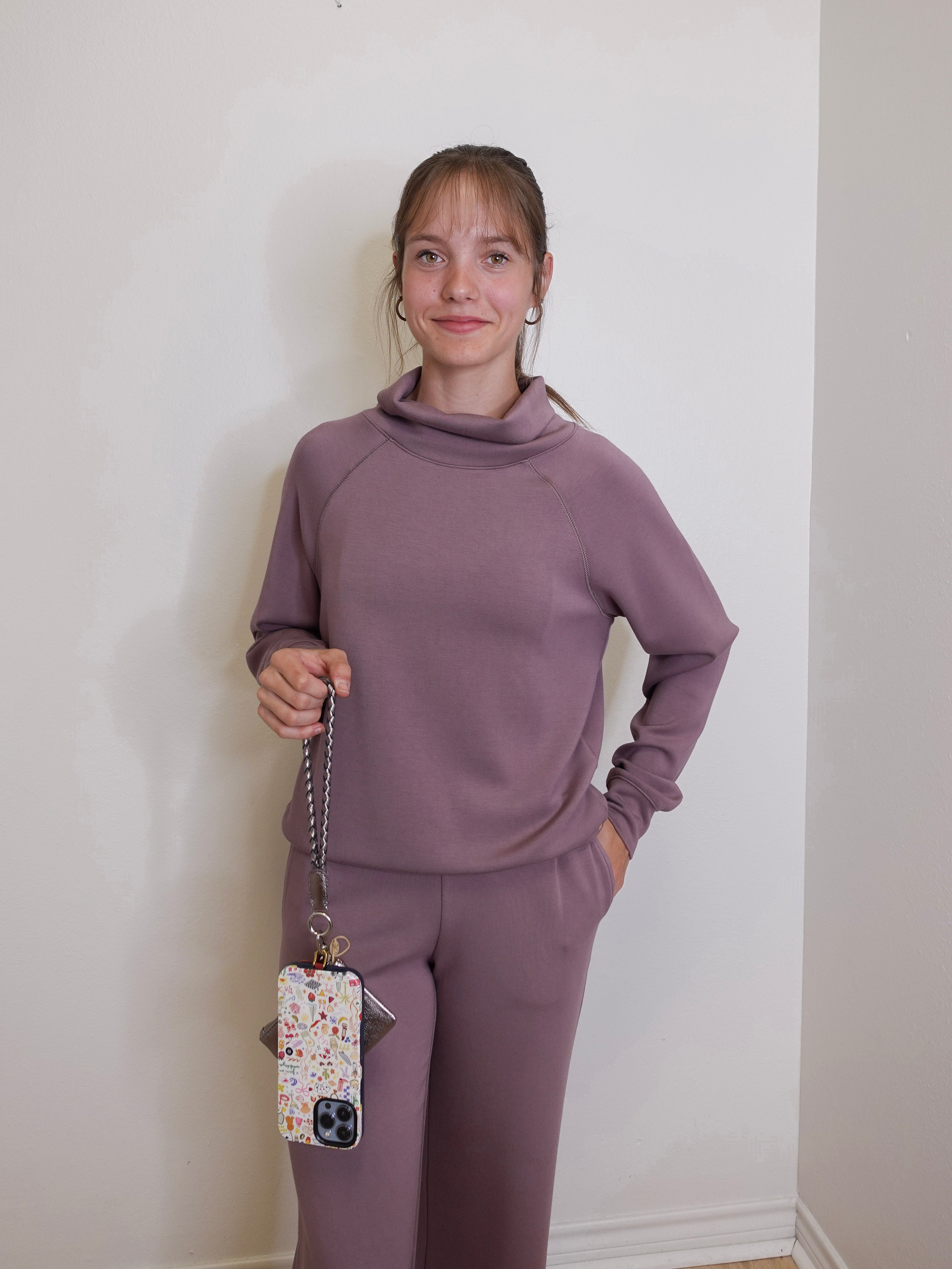 woman holding the Hobo lasso phone wristlet in metallic leather, color pewter spur against a white background. 