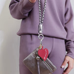  woman holding the Hobo lasso phone wristlet in metallic leather, color pewter spur against a white background. 