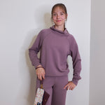 woman modeling the lasso phone wristlet in pebbled leather mulberry glaze color against a white background. 