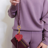 woman modeling the lasso phone wristlet in pebbled leather mulberry glaze color against a white background. 
