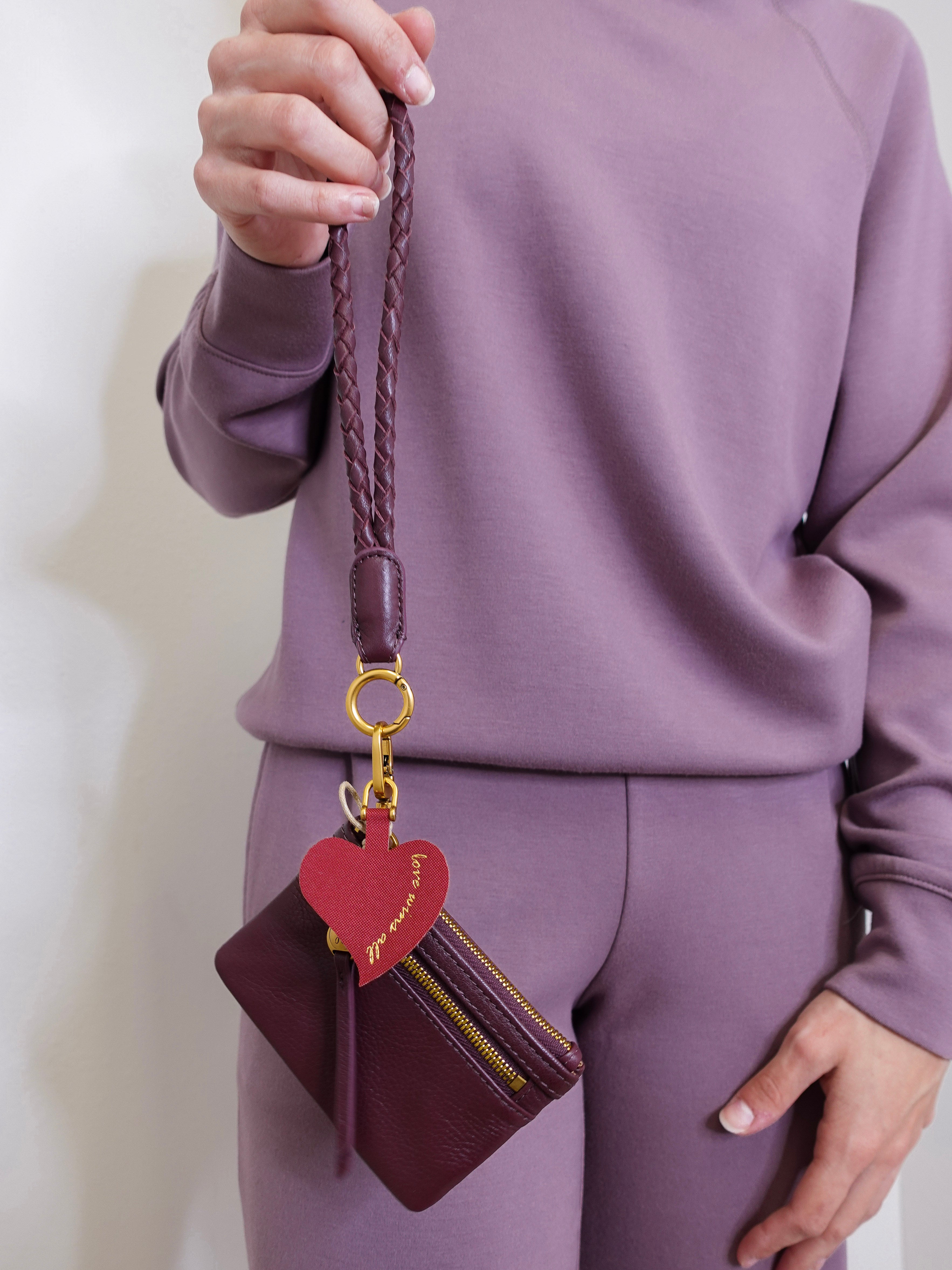 woman modeling the lasso phone wristlet in pebbled leather mulberry glaze color against a white background. 