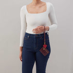 woman holding the lasso phone wristlet in pebbled leather mulberry glaze color against a white background. 