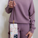 woman modeling the lasso phone wristlet in pebbled leather mulberry glaze color against a white background. 