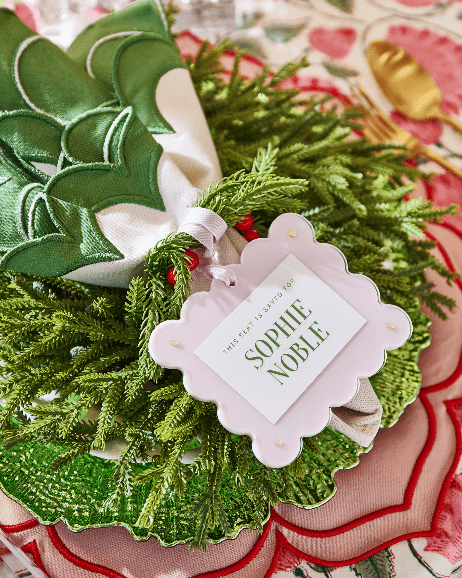 Decorative green wreath with a 'Sophie Noble' tag on a patterned surface.