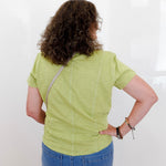 Person wearing a green shirt and blue jeans against a white background