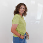 Woman wearing a green shirt and blue jeans against a white background