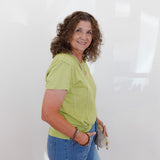 Woman wearing a green shirt and blue jeans against a white background