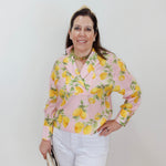 Woman wearing a pink blouse with lemon pattern against a white background