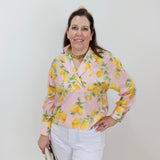 Woman wearing a pink blouse with lemon pattern against a white background
