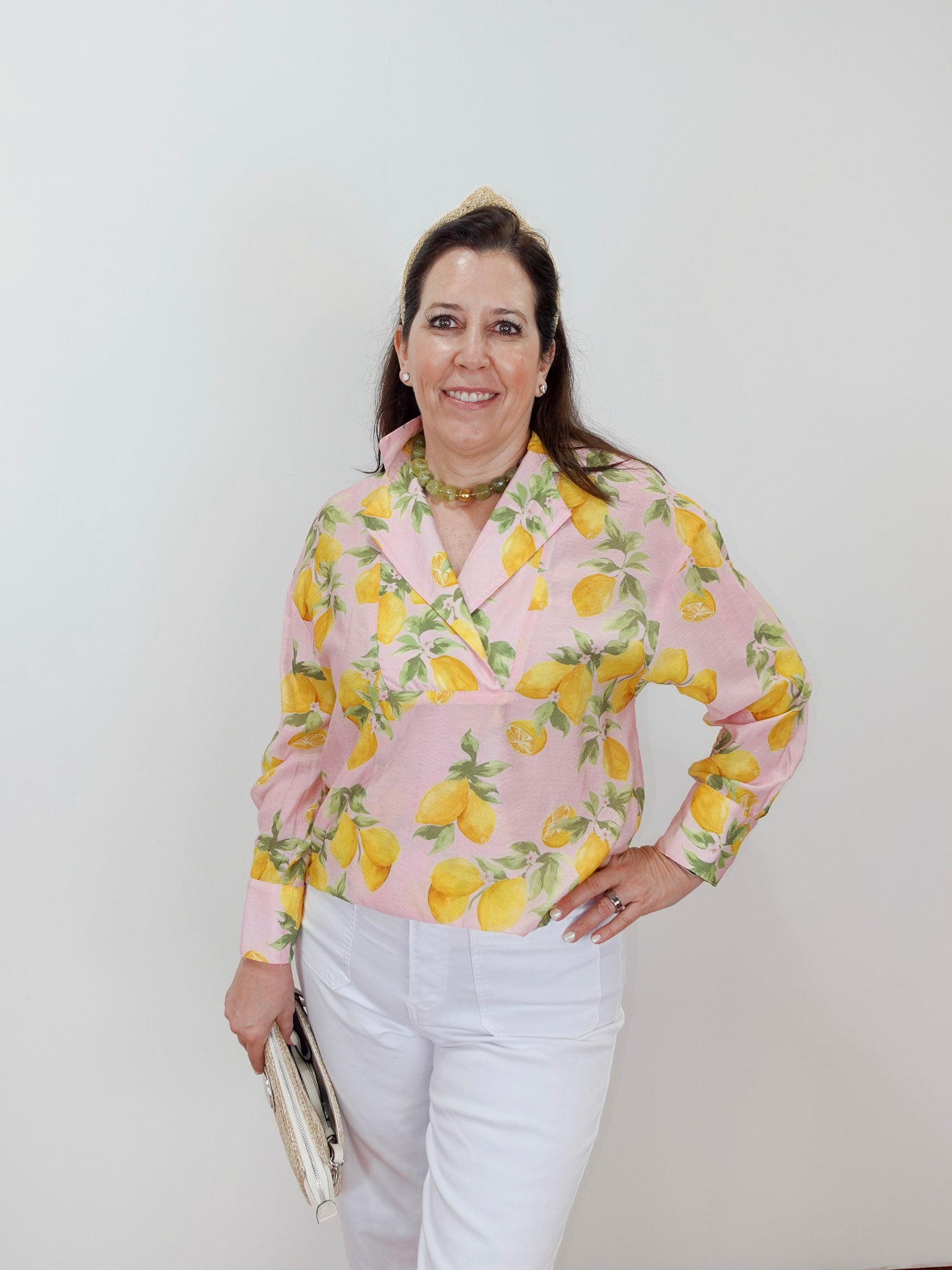 Woman wearing a pink blouse with lemon pattern against a white background