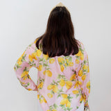 Person wearing a pink blouse with lemon print against a white background