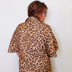 Person wearing a leopard print shirt against a white background