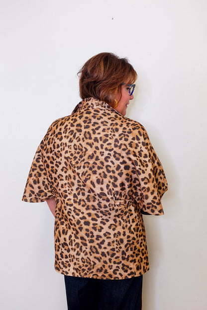 Person wearing a leopard print shirt against a white background