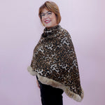 Person wearing a leopard print poncho with fur trim against a plain background