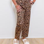 Person wearing a leopard print outfit with white shoes on a plain background