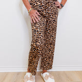 Person wearing a leopard print outfit with white shoes on a plain background