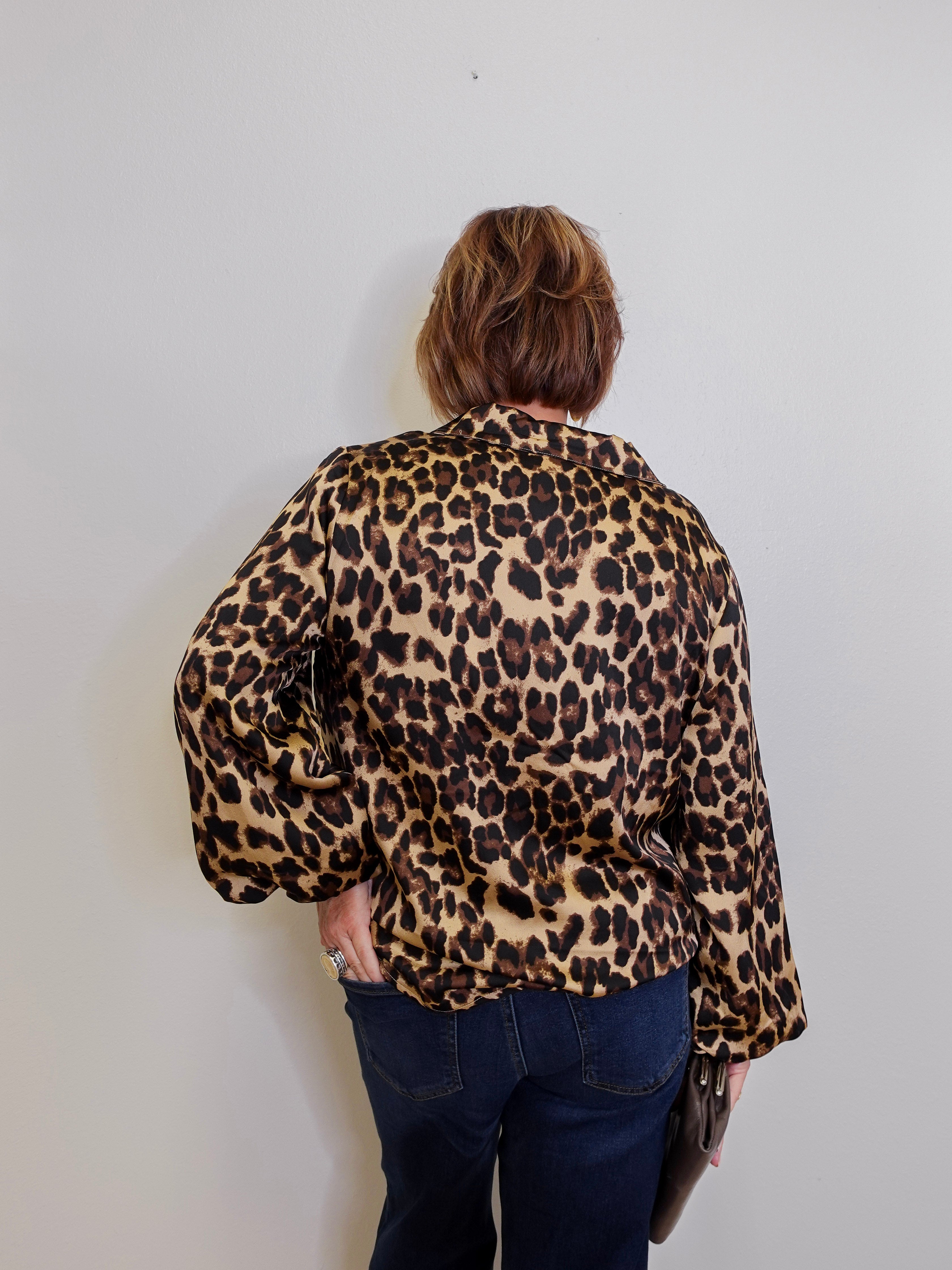 Person wearing a leopard print blouse against a plain background
