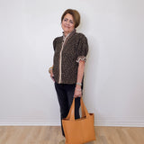 Woman holding a brown tote bag against a white wall