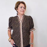 Woman wearing a leopard print blouse with a white wall background