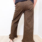 Person wearing leopard print pants with a plain background