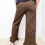 Person wearing leopard print pants with a plain background