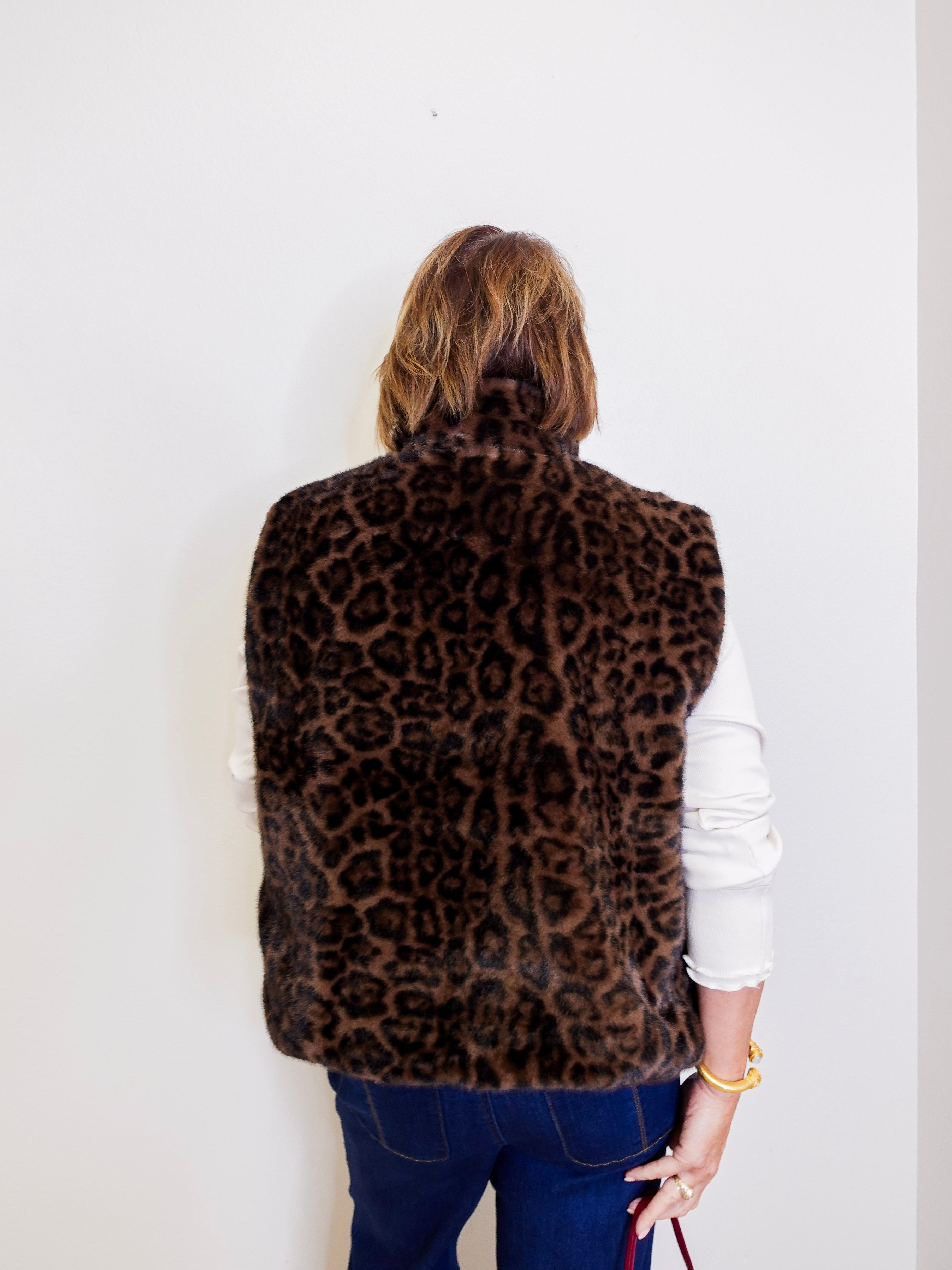 Person wearing a leopard print vest against a white background
