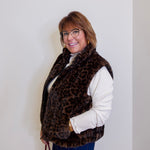 Person wearing a leopard print vest against a plain background
