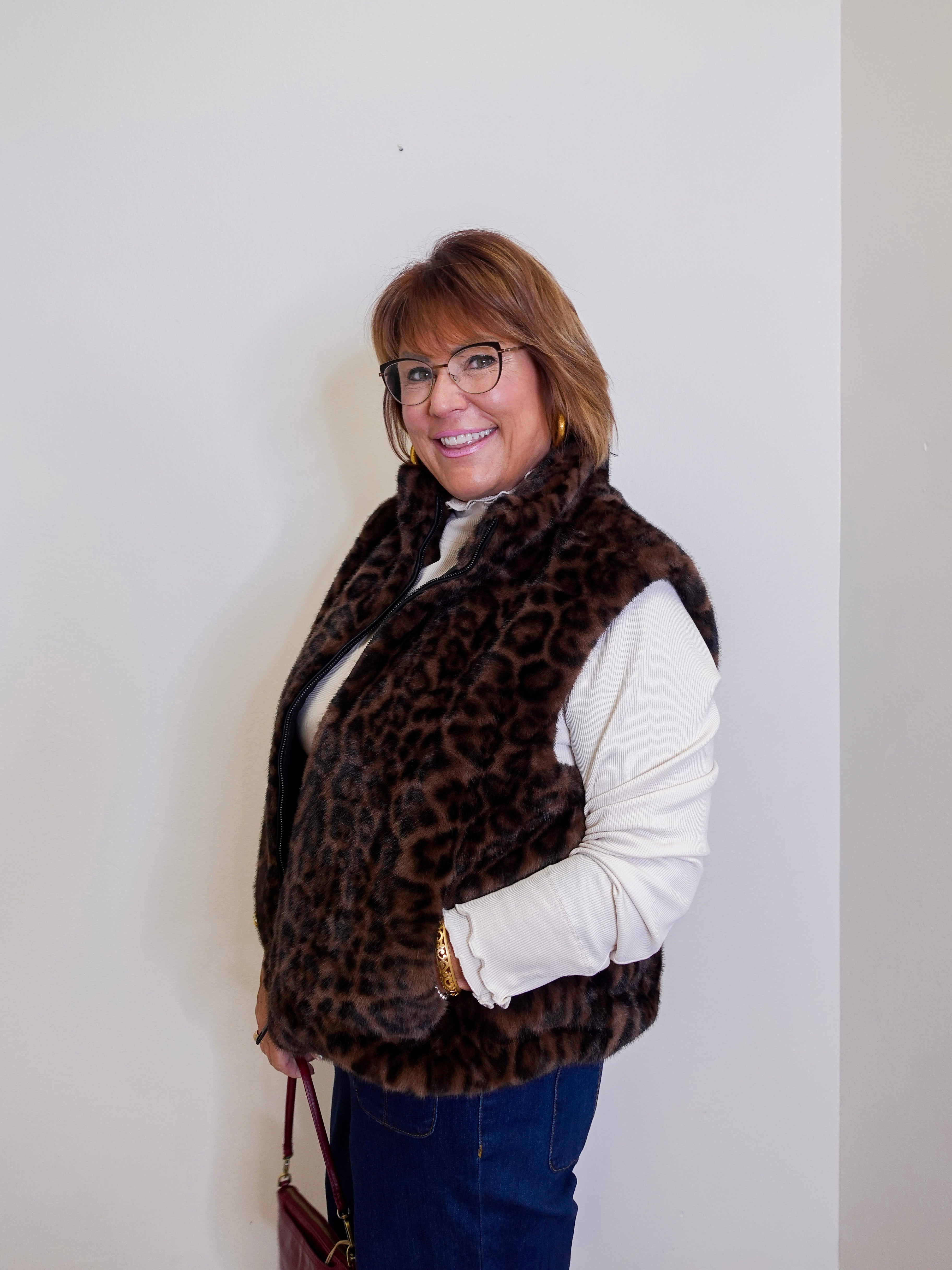 Person wearing a leopard print vest against a plain background