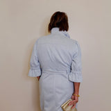 Person wearing a light blue dress against a plain background