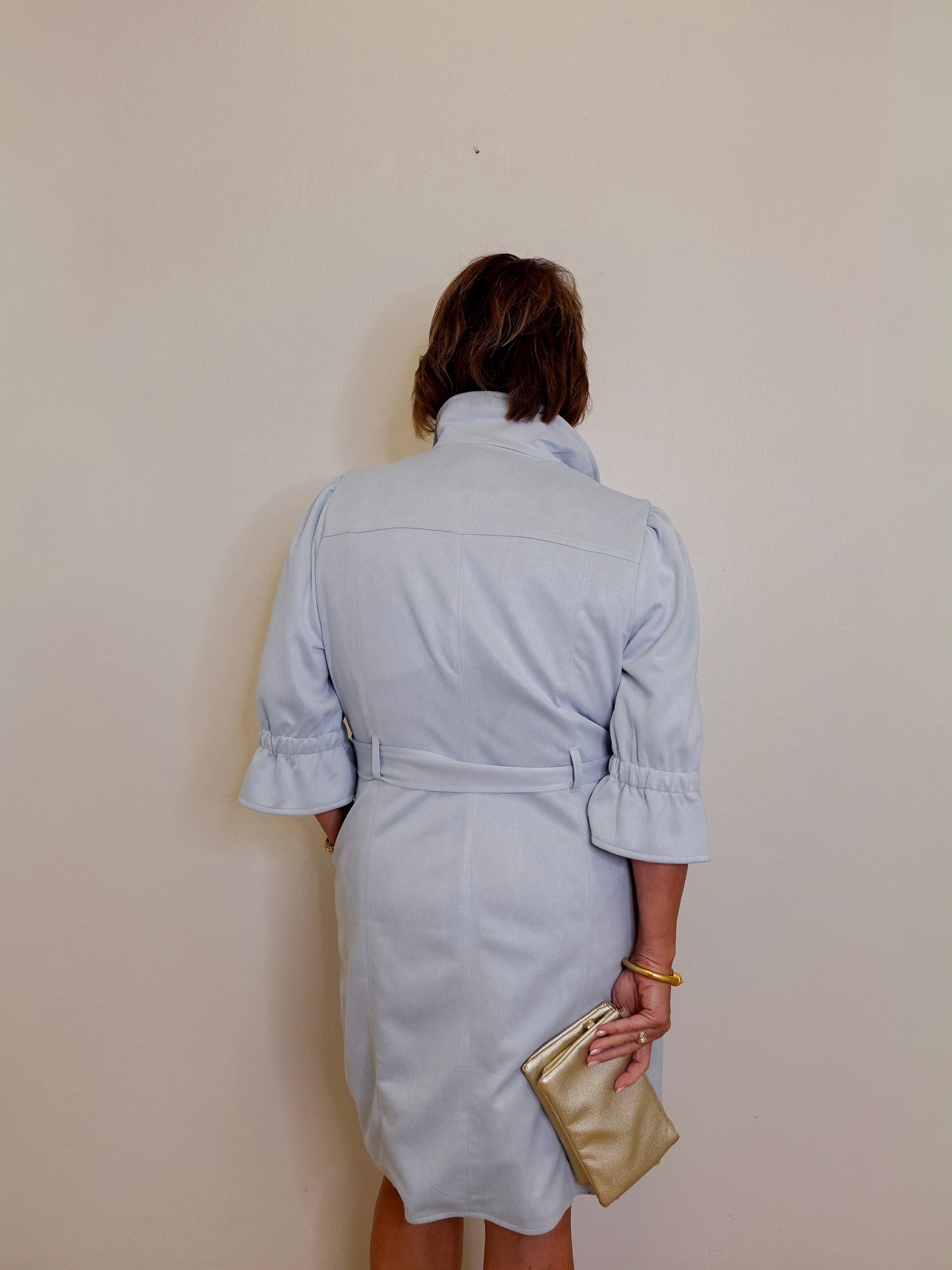 Person wearing a light blue dress against a plain background