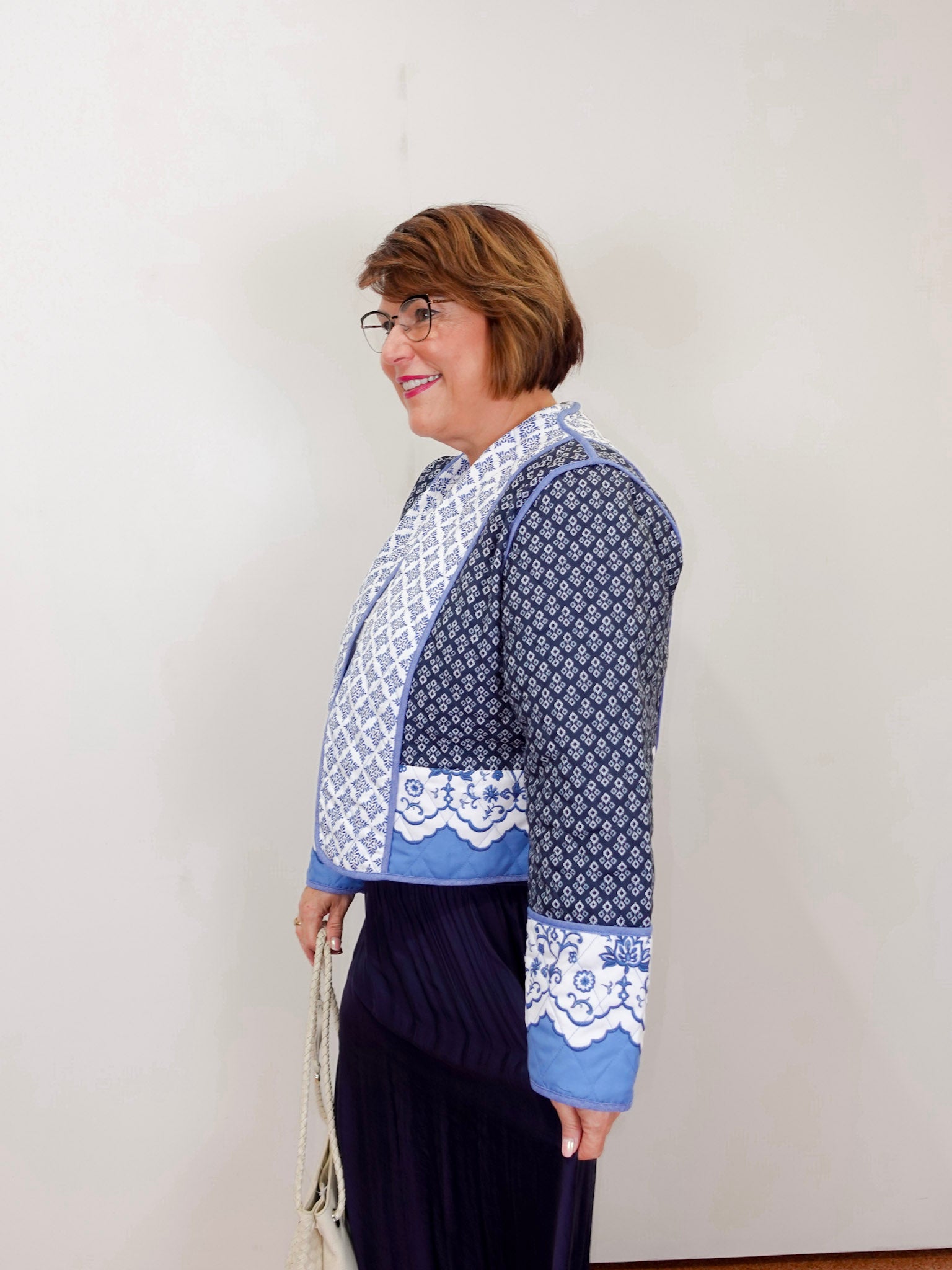 Woman wearing a reversible quilted jacket with blue and white patterns styled over a white top.