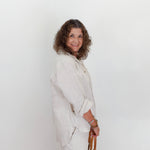 Woman wearing a light-colored outfit against a white background