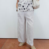 Person wearing a polka dot shirt, light pants, and sandals on a plain background