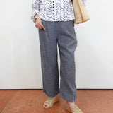 Person wearing a patterned shirt, gray pants, and sandals on a plain background