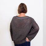 women wearing a brown sweater against a white wall. 