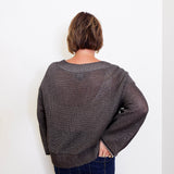 women wearing a brown sweater against a white wall. 