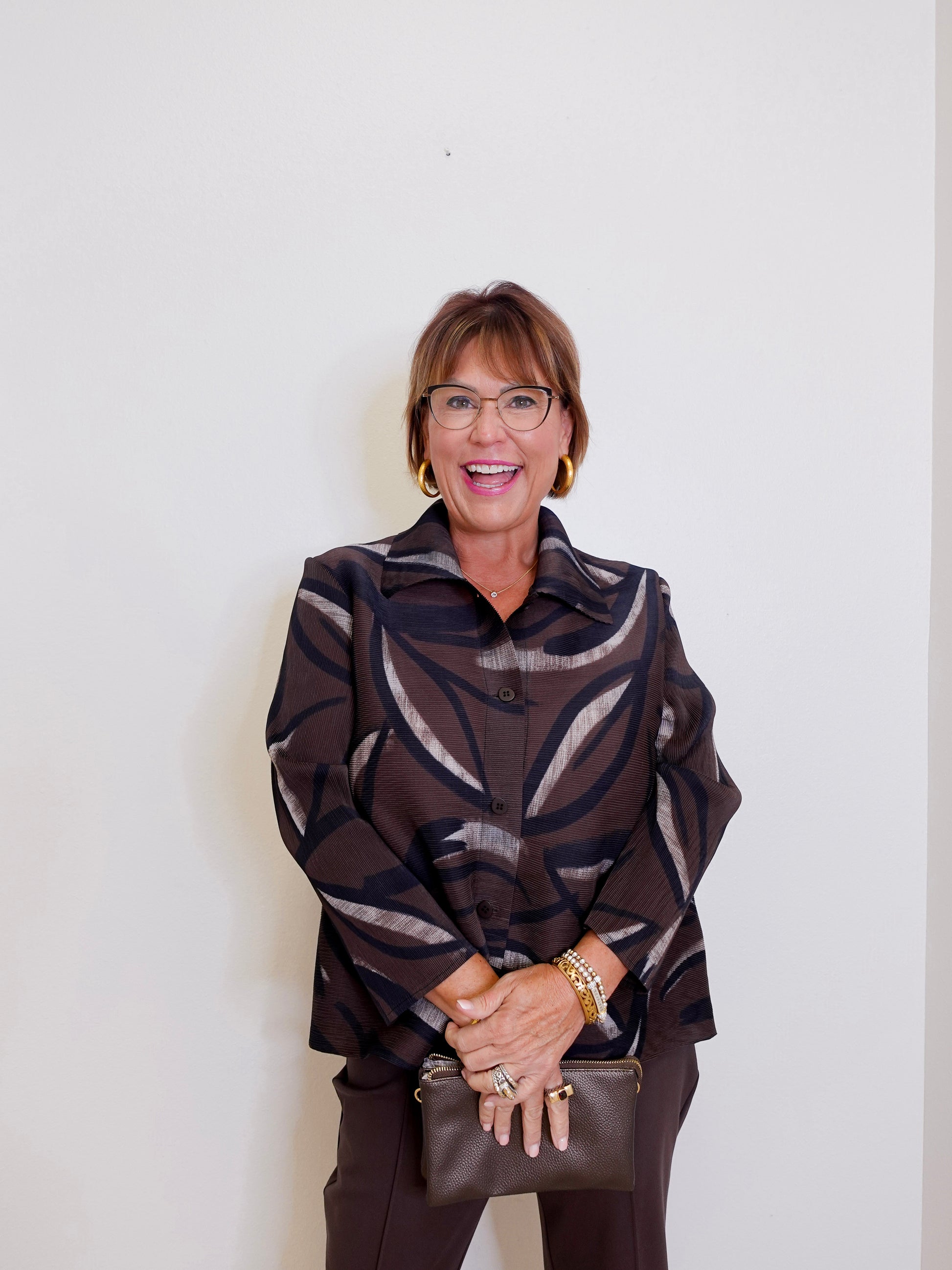 woman wearing a brown nigh out jacket blouse in brown against a white background. 