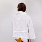 Person wearing a white shirt sitting on a chair with a white background