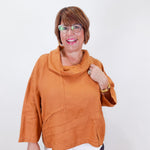 Woman wearing an orange sweater with a white background