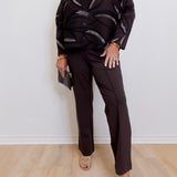 woman wearing a brown pant against a white background. 
