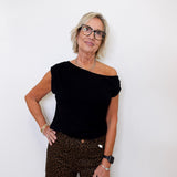 Woman wearing a black top and leopard print pants against a white background