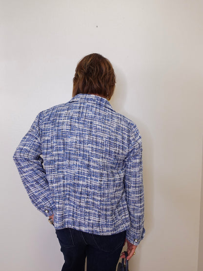 Person wearing a blue plaid shirt against a white wall