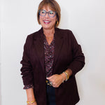 Woman wearing a brown blazer and glasses against a white background