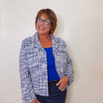 Woman wearing a blue and white patterned jacket over a blue top against a plain background