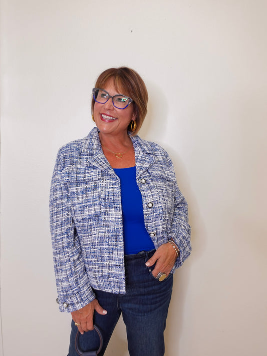 Woman wearing a blue and white patterned jacket over a blue top against a plain background