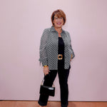 Woman wearing a polka dot shirt and black pants against a plain background