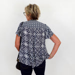 Person wearing a black and white patterned shirt against a white background